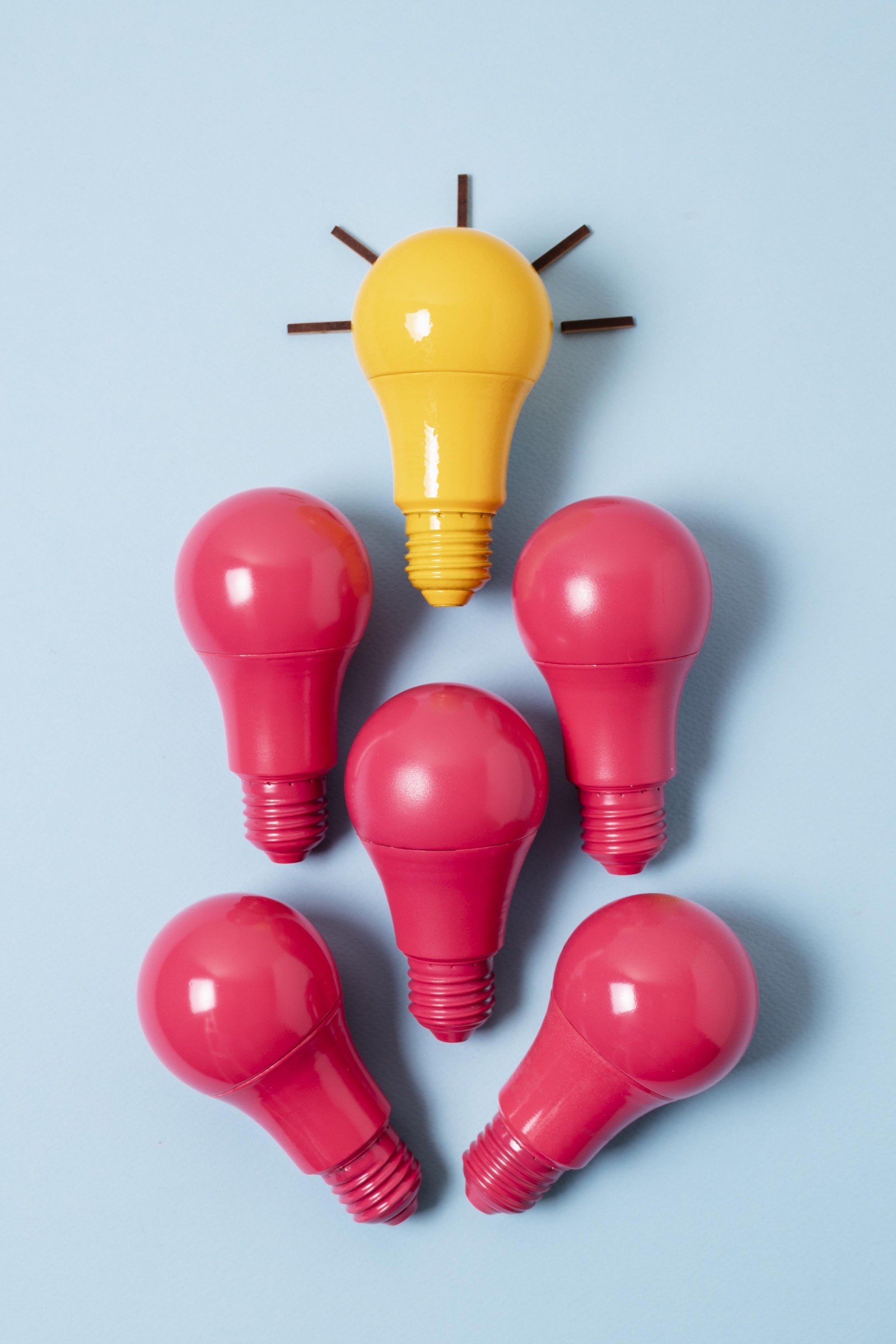 One yellow light bulb standing out among red light bulbs